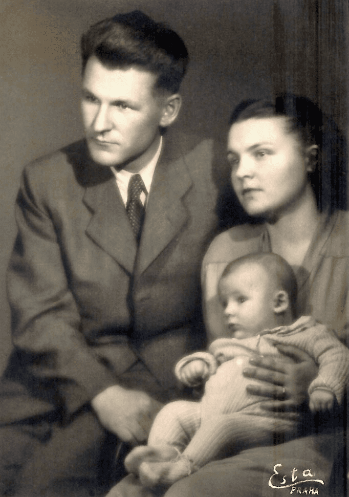 Young family portrait. Man in suit and tie, woman holding baby.