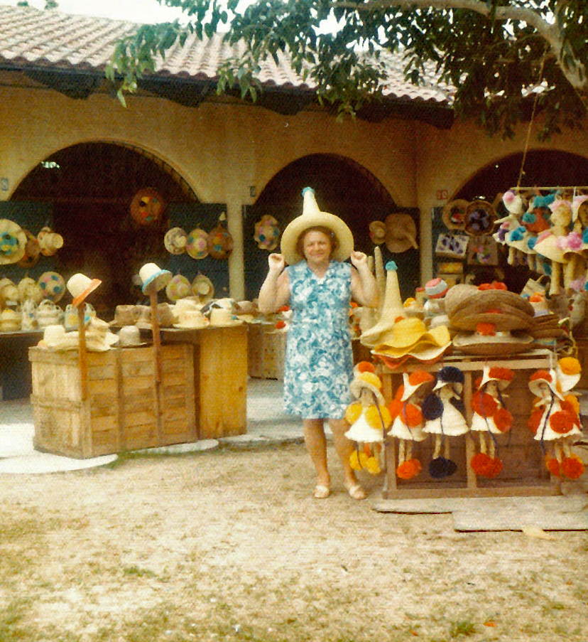 Woman at hat store in Mexico trying on a straw hat.