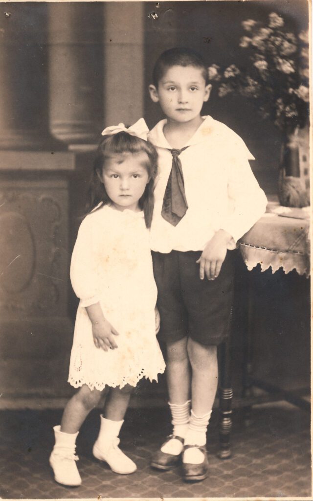 Young boy and his sister having their photograph taken in the early twentieth century. Sepia photo.