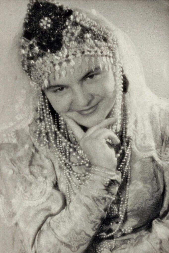 Old photo of young woman wearing Russian costume and smiling.