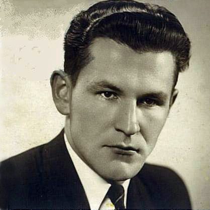 Portrait of handsome man with dark hair, wearing a suit and tie and a serious expression.