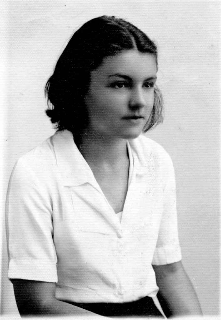 Young woman wearing white blouse with short hair and serious expression.