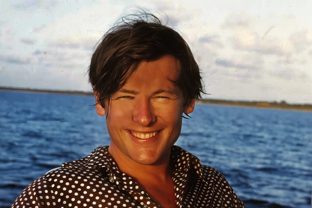 suntanned handsome young man with a silly grin by the ocean.