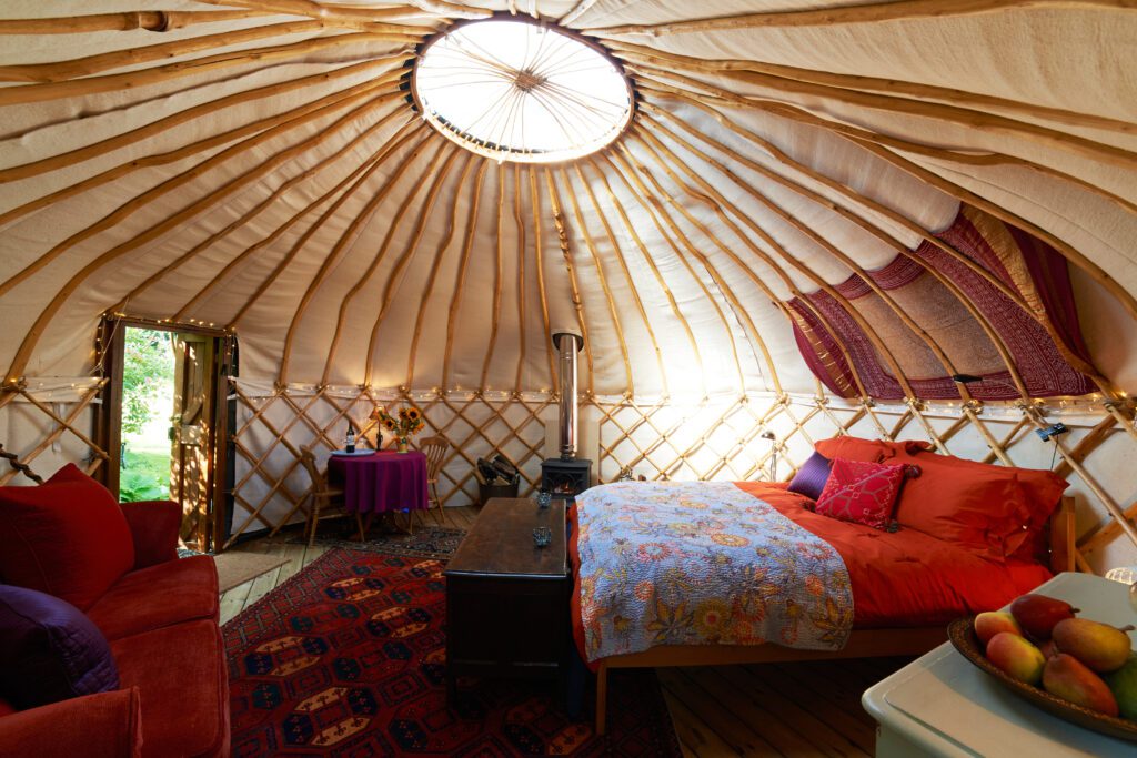 fancy, bohemian yurt interior with wood ribbed dome ceiling and colorful bedding and furnishings.